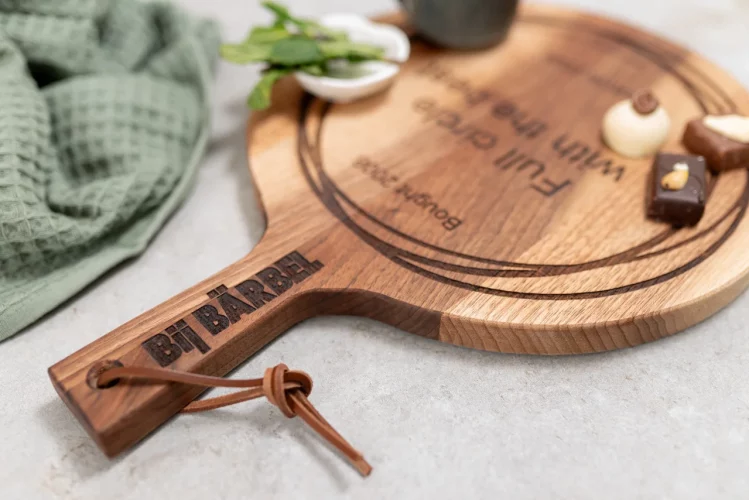 Detailfoto handvat van ronde notenhouten tapasplank met handvat, daarop bonbons en muntthee. Bovenop een theedoek. Gemaakt door Puntgaaf made personal